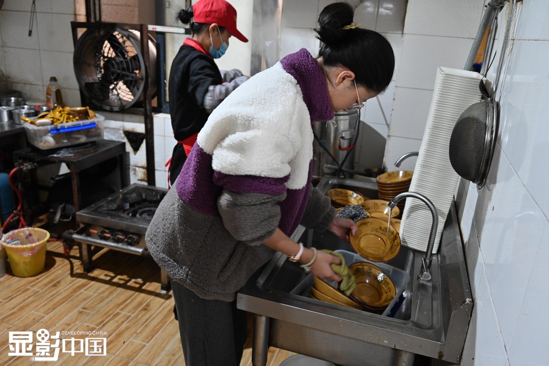 11月21日是周日，王素侠的女儿孙奥宇在后厨帮助妈妈洗碗。新华网发（杨晓原 摄）