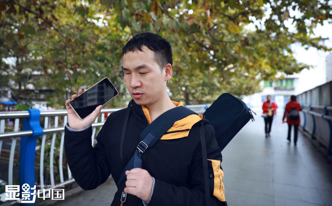 上班路上，杨林一边走一边用手机听曲子，除了工作时间，音乐几乎占据了他生活的全部（11月3日摄）。新华网 卢志佳 摄