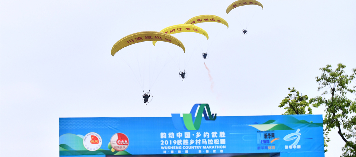 在起跑拱门上方，飘着为跑友鼓劲儿的动力伞