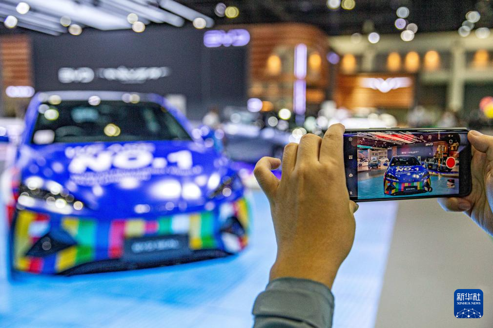 3月27日,一名观众在泰国曼谷国际车展上拍摄比亚迪海豹汽车.