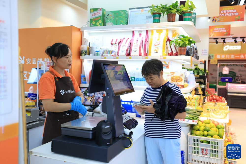 资料照片:8月27日,深圳保障房社区商铺工作人员接待顾客