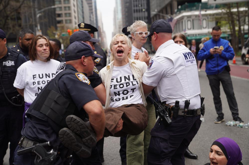 4月13日，在美国纽约曼哈顿，一名参加抗议活动的女子被警察控制。当日，民众在美国纽约曼哈顿举行反对战争、声援巴勒斯坦，以及反对美国移民与海关执法局驱逐移民的抗议活动。新华社记者张凤国摄